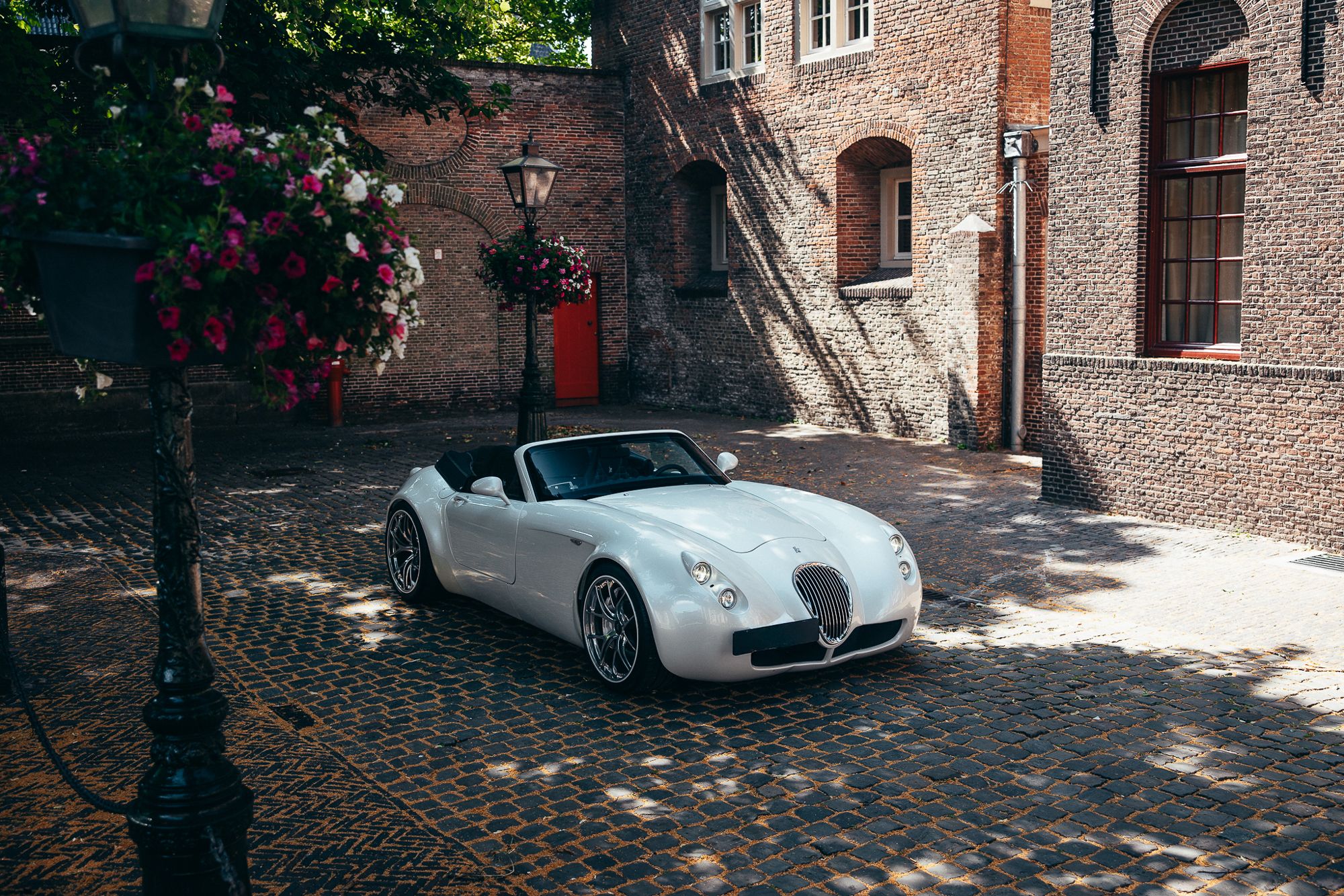 Wiesmann Roadster op een binnenplaats met bloemen